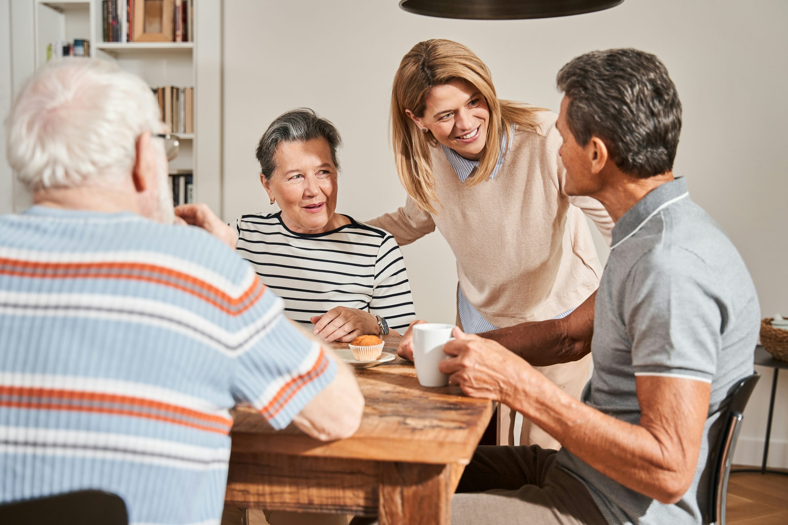 Family and a caregiver sharing coffee and conversation at a table